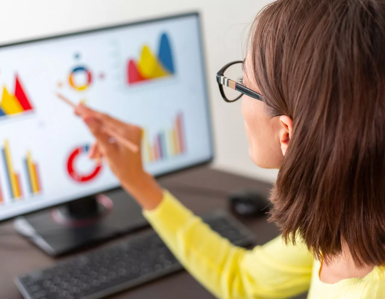 Femme analysant des graphiques sur écran d'ordinateur.